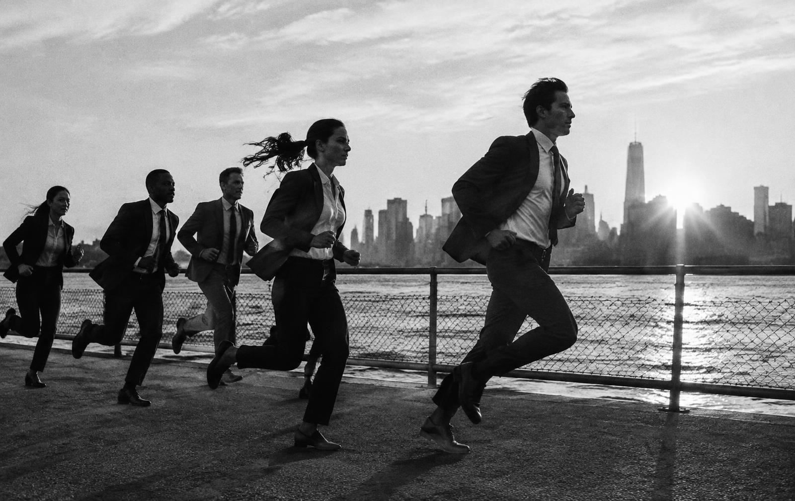 Executives running along a waterfront at sunrise